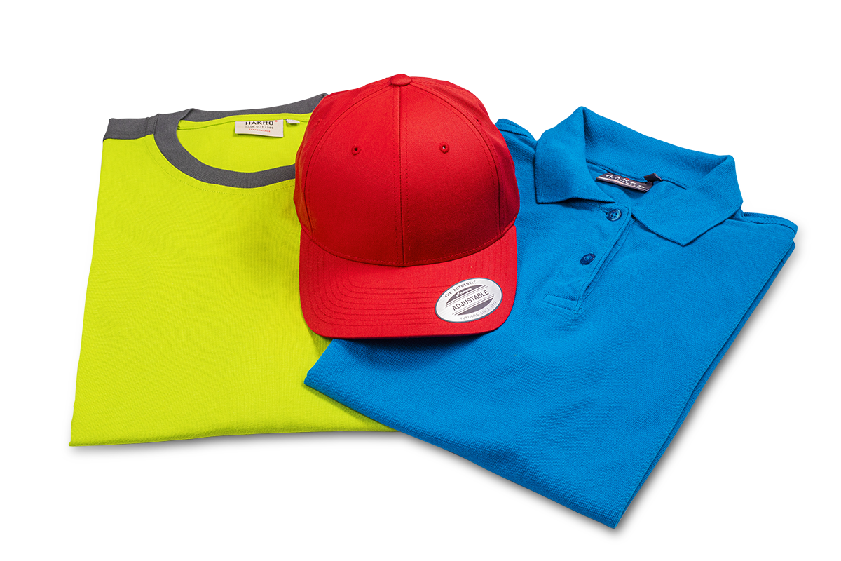 Stoffmuster für Shirt, Cap und Poloshirt Rotes Baseball-Cap liegt auf grünem Shirt mit grauem Rundhalsausschnitt sowie einem blauen Poloshirt